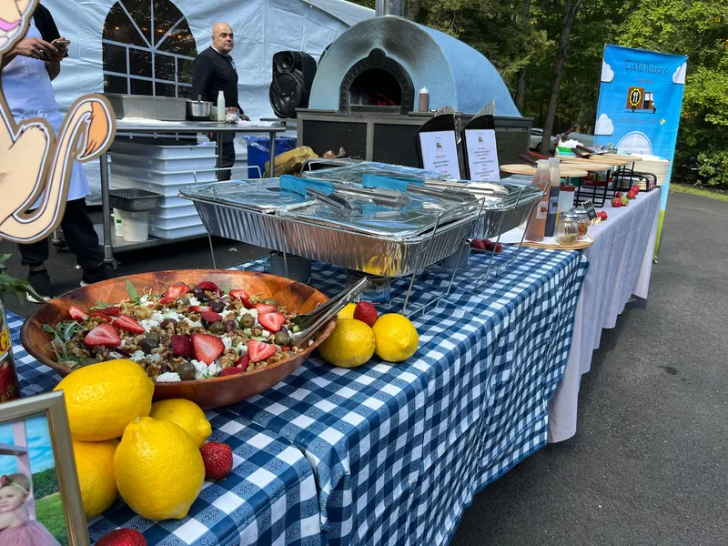 A Culto Italiano catering buffet with strawberries and lemons on a gingham table