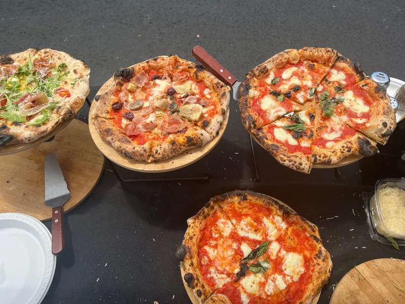 Four Neapolitan pizzas on wooden boards, ready to serve