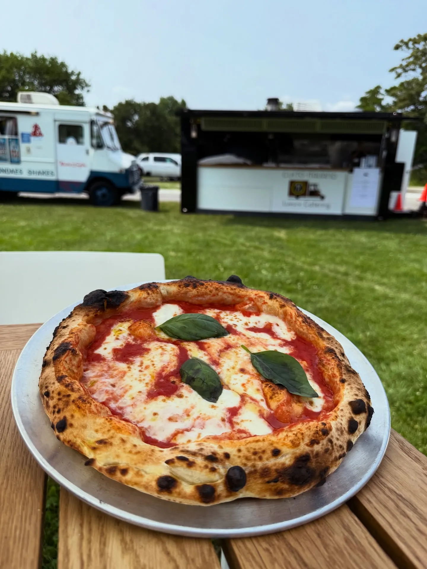 A wood-fired Margherita, fresh from the oven, at an outdoor party