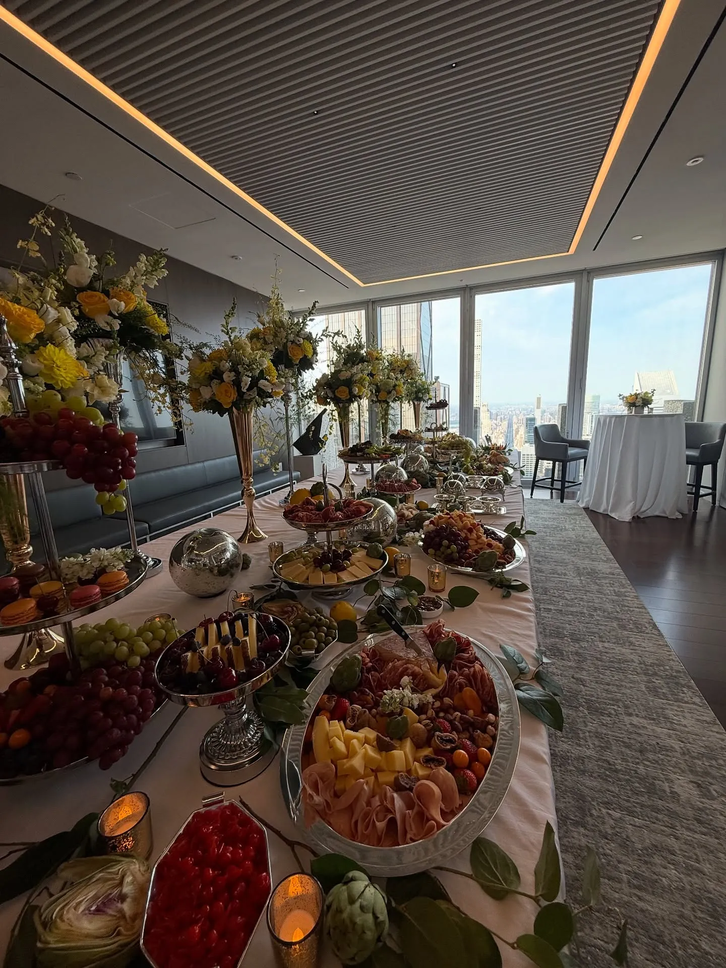 A reception designed by Culto Italiano high above Manhattan: long dressed table, tall florals, candles