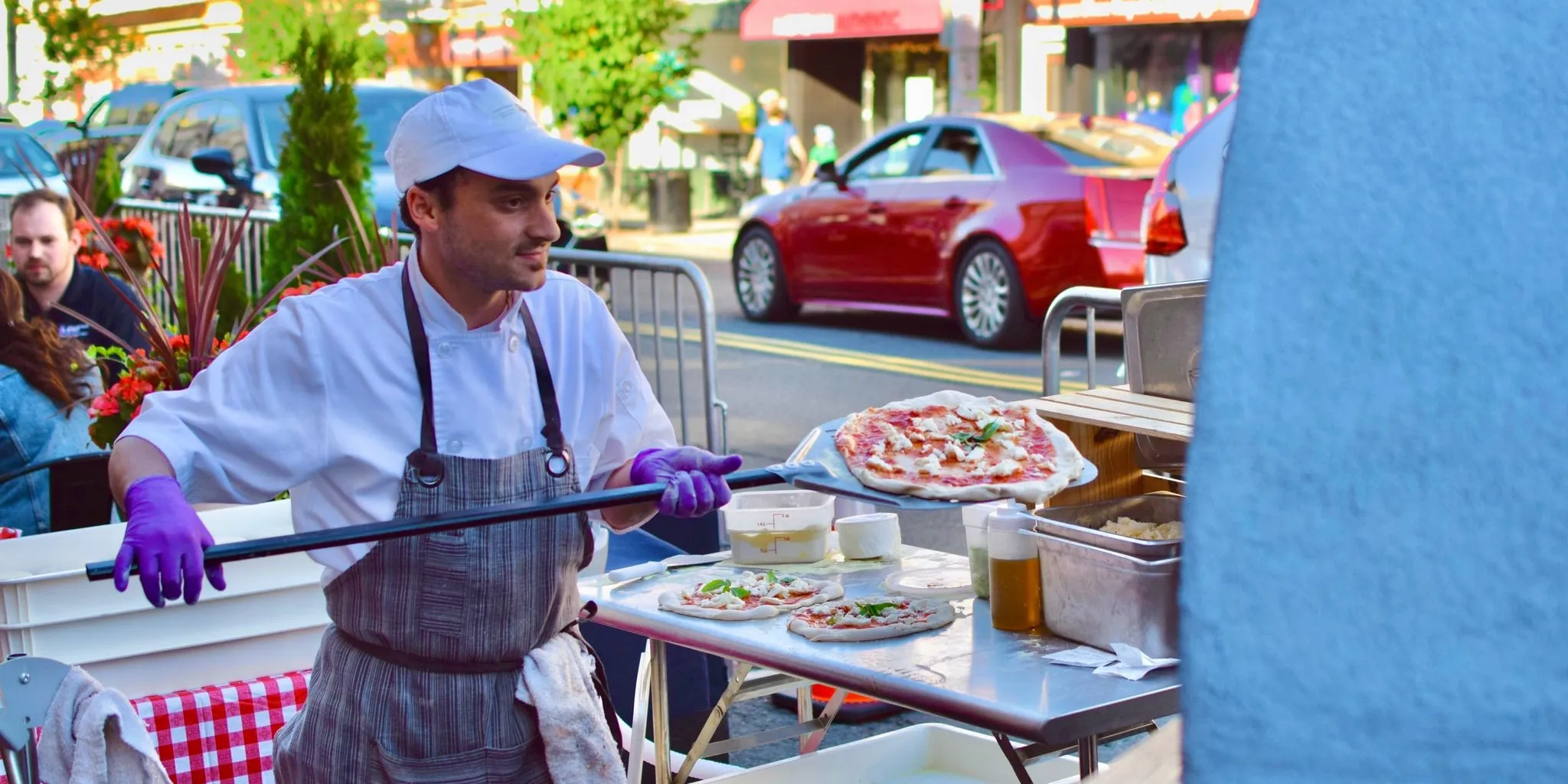 A Culto Italiano chef finishing a fresh Margherita pizza from a portable wood-fired oven