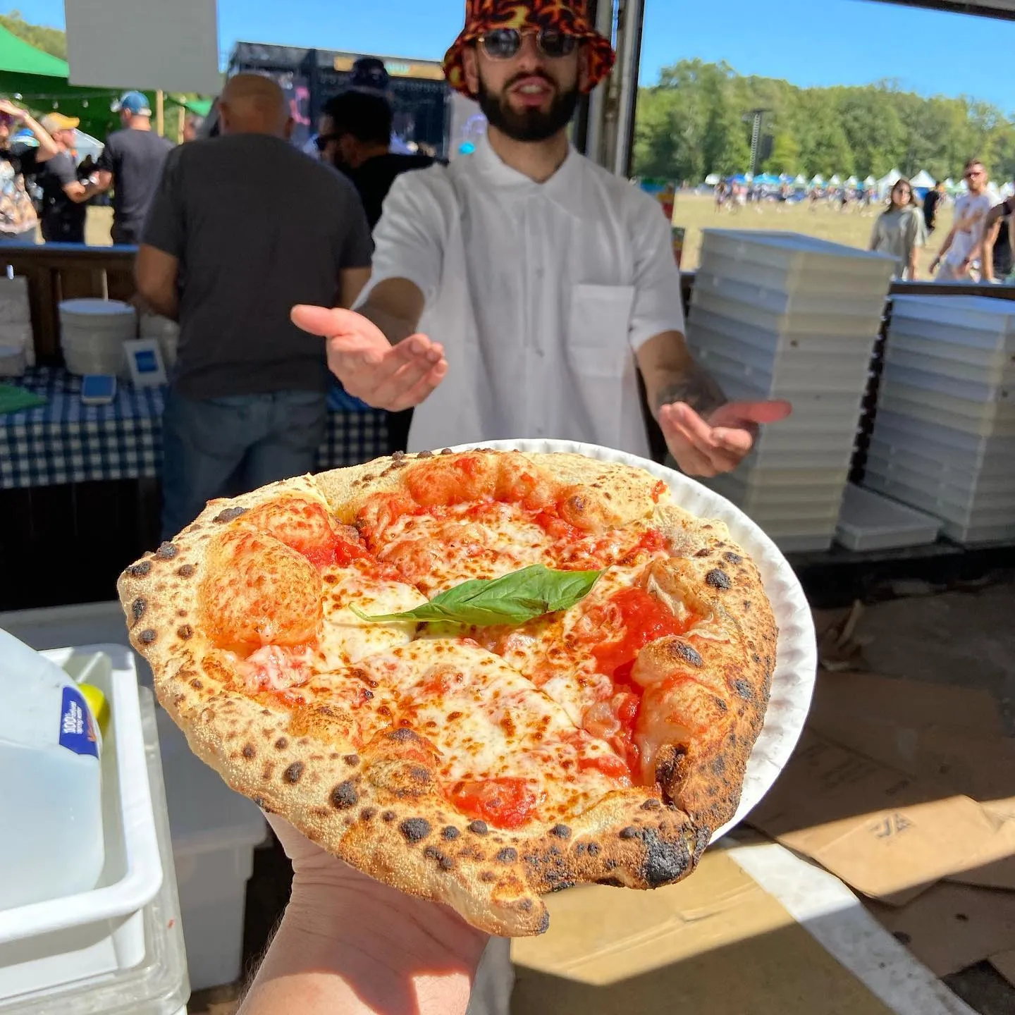 A Culto Italiano chef handing a freshly baked Margherita pizza to a guest at an outdoor festival