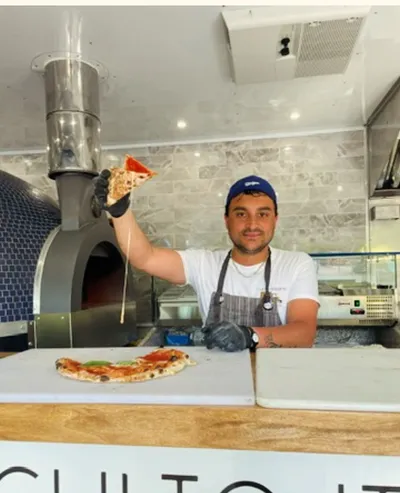 A pizzaiolo holding up a slice of Neapolitan pizza at the Pizza Truck