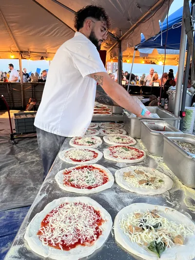 Neapolitan pizzas being topped at an outdoor event