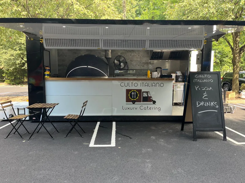 The Culto Italiano Pizza Truck set up with bistro tables and a chalkboard menu